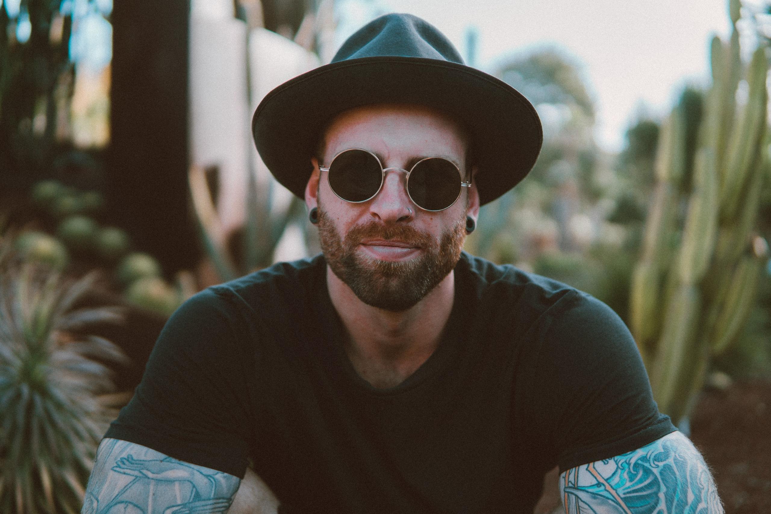 tattooed man in sunglasses and hat