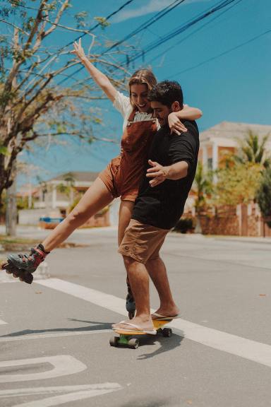 A couple on a skateboard and roller blades laughs.
