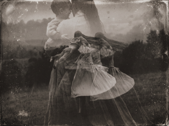 Sepia-toned double-exposure of two figures embracing and dancing outdoors, their forms layered and blurred to suggest motion across time.