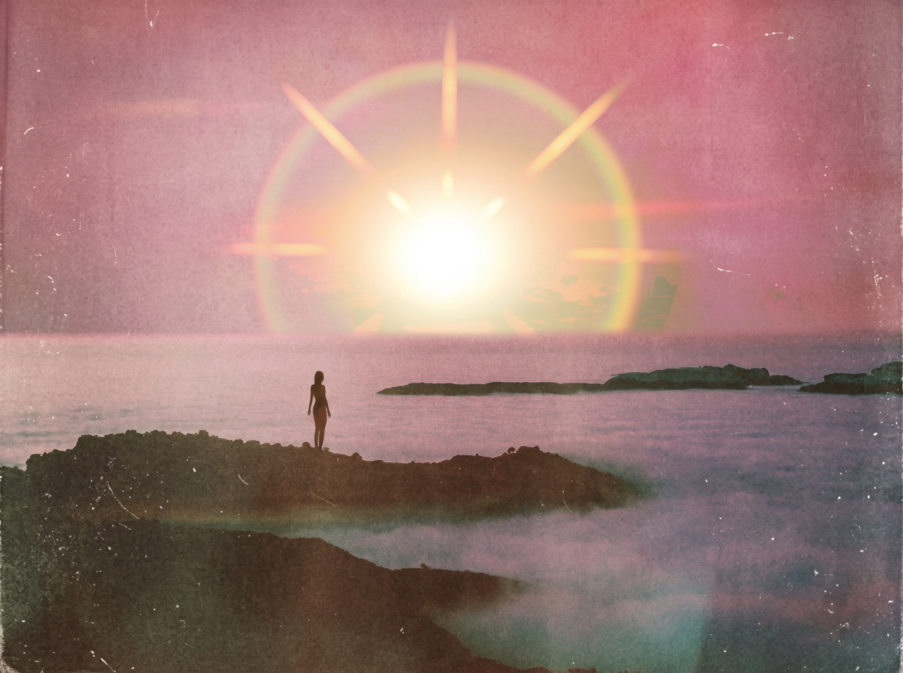 Silhouette of a person standing on rocks by the ocean, facing a bright sunburst surrounded by a rainbow halo in a pink sky.