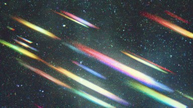 Multiple colorful light streaks resembling meteors cutting diagonally across a dark, star-speckled sky
