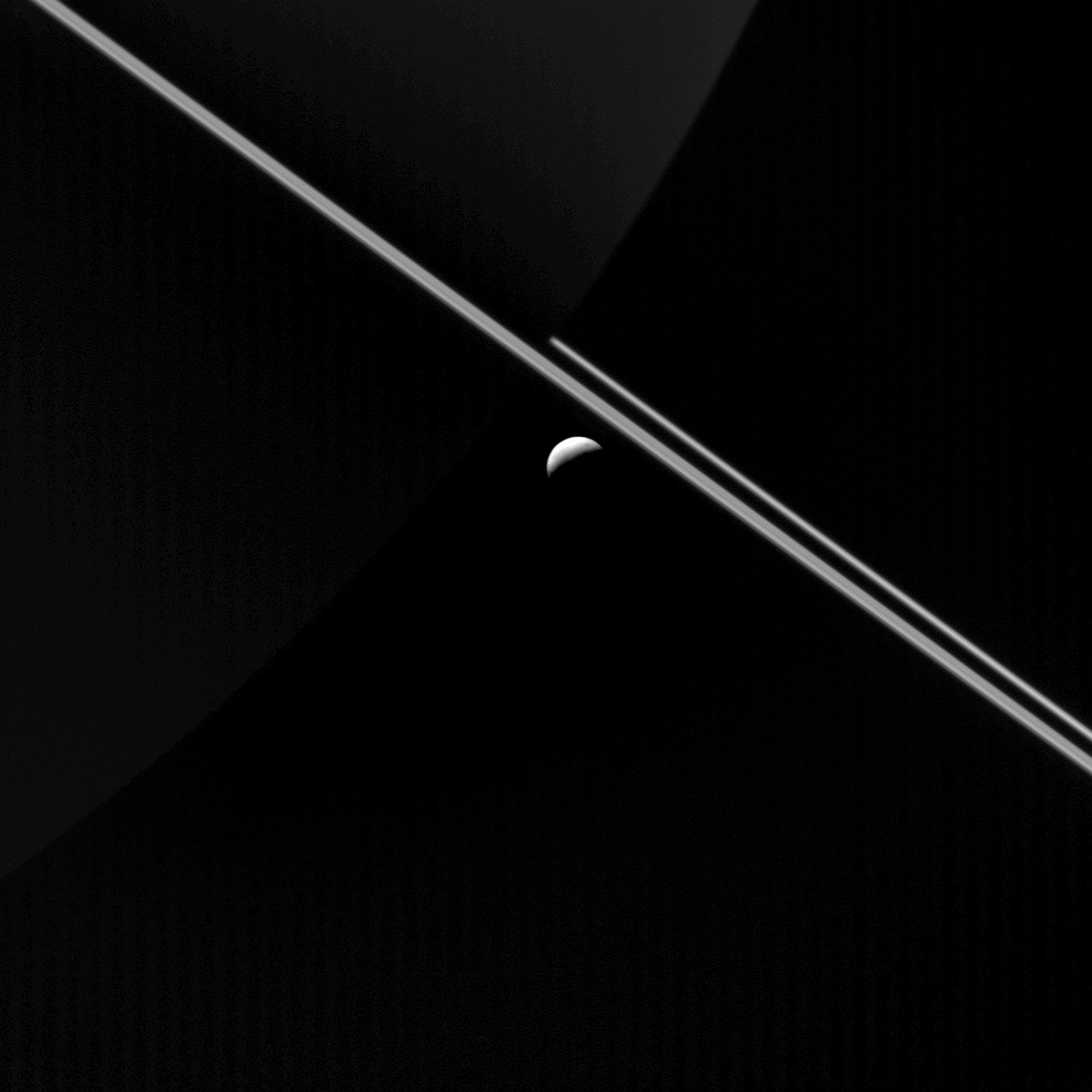 Saturn's rings glowing in sunlight with the icy moon Enceladus visible nearby, photographed by NASA's Cassini spacecraft