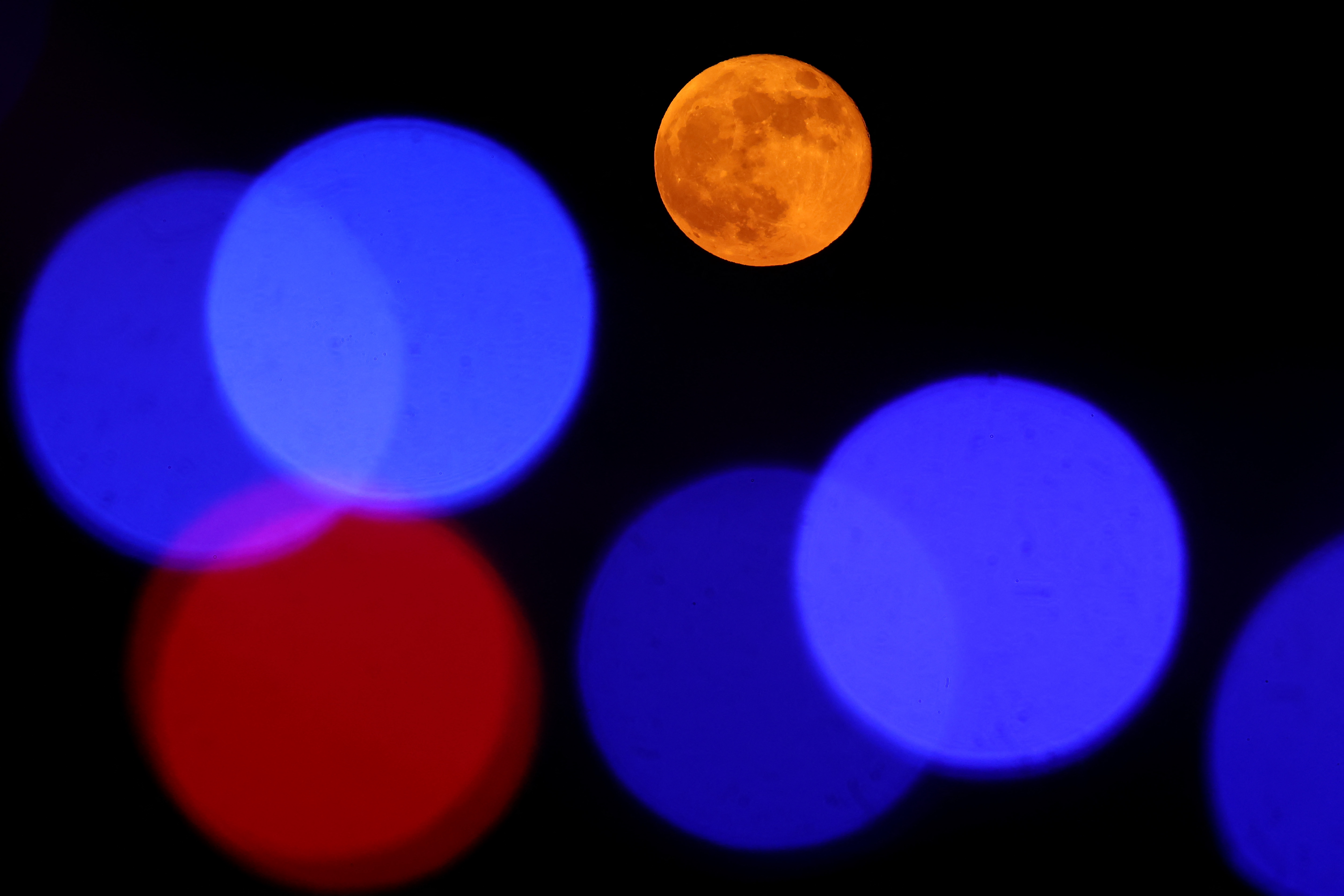 Full Harvest Moon rising behind a mosque silhouetted against the night sky in Doha, Qatar