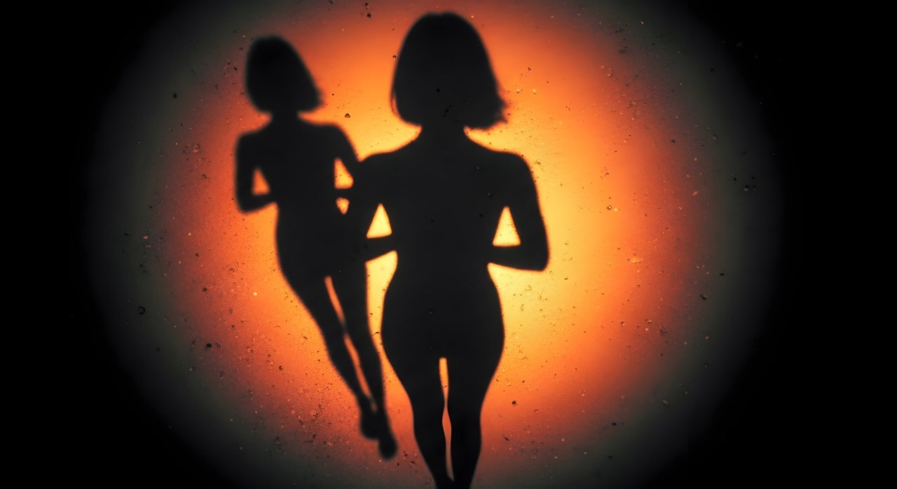 Silhouette of Two Women against a Textured Orange and Black Background AI-assisted library description: Two stylized silhouettes stand against a warm orange glow and dark textured background. Themes: identity, connection, confidence, relationships.